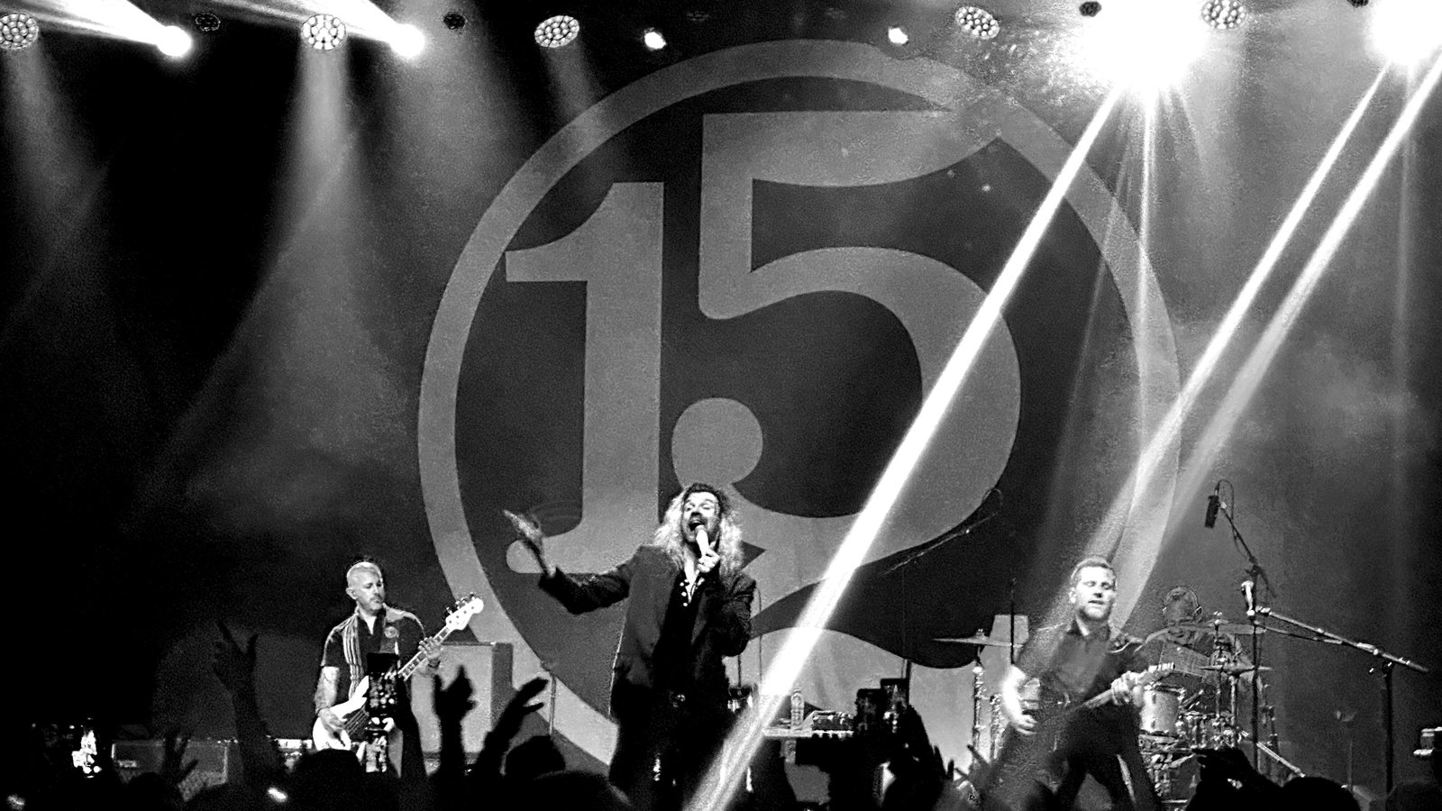 Taking Back Sunday on stage beneath the 152 backdrop, beams of light cutting across the band and the crowd’s hands up in the foreground